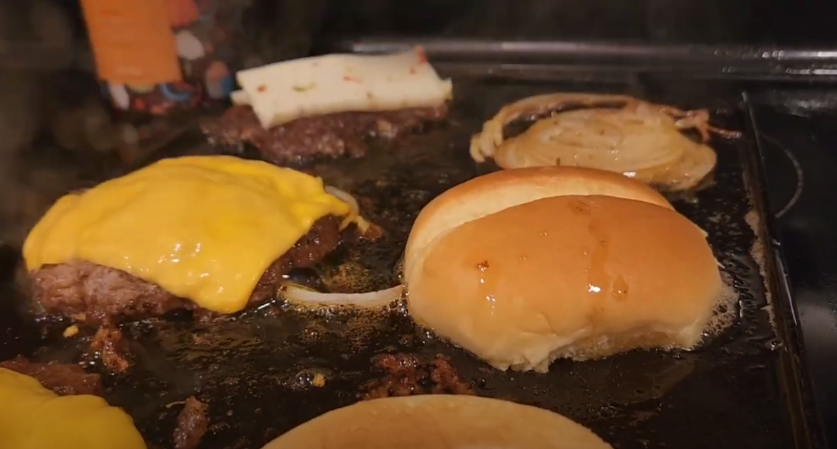 Grilling smash burgers and buns on cast iron griddle